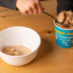 Scooping decaf coffee ice cream into a bowl.