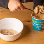Using a spoon to put ice cream into a white bowl.